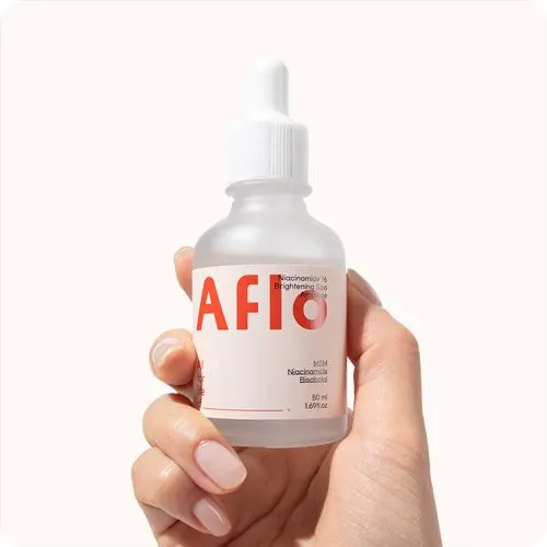 투명한 병에 담긴 나이아신아마이드 세럼을 손으로 들고 있는 장면으로, 미니멀한 디자인의 용기와 깨끗한 배경이 제품의 순한 이미지를 강조한다. (A hand holding a niacinamide brightening serum bottle with minimalist packaging against a clean background, highlighting its gentle and pure formulation.)