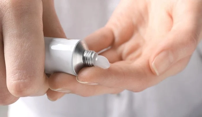 피부 장벽 회복을 위한 보습 크림을 손가락에 덜어내는 장면으로, 무너진 피부 보호막을 강화하고 수분을 공급하는 스킨케어 단계를 표현했다. (Applying moisturizing cream to restore the skin barrier and lock in hydration.)